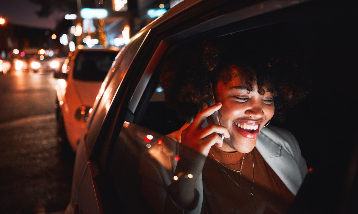 A passenger on the phone in the back of a car at night