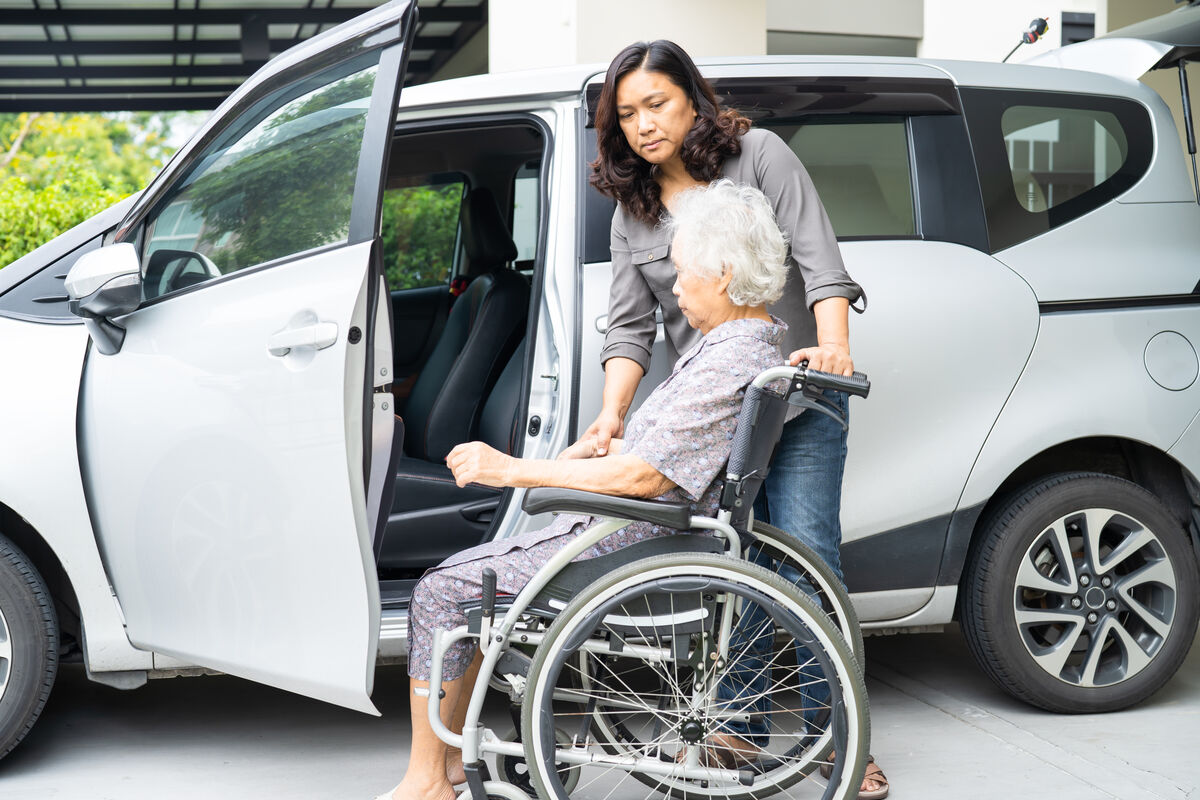 A support worker helping a participant beside an open vehicle door