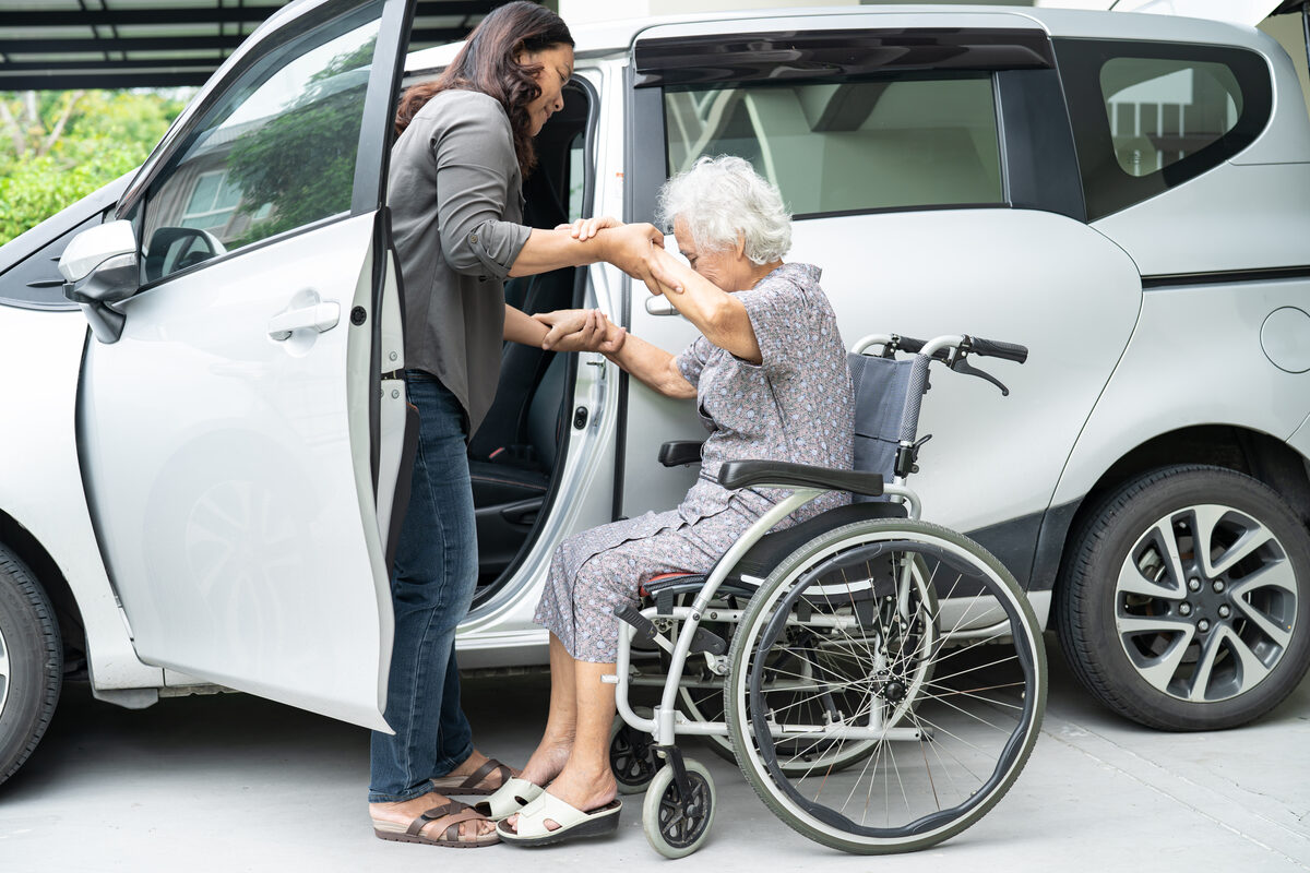 A carer helping an older passenger into an accessible taxi