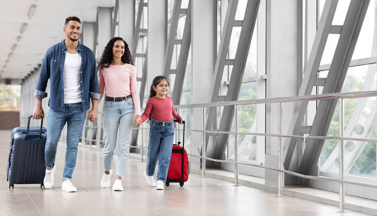 A family with suitcases walking through an airport terminal