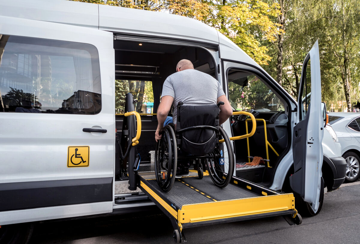 A wheelchair user boarding an accessible van over the lift platform