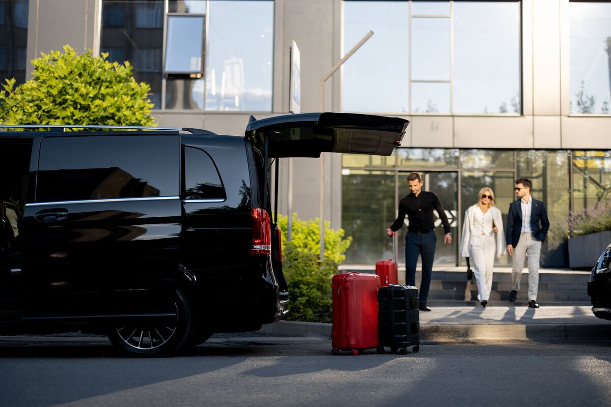 A Quick Maxi Cab van waiting with luggage loaded outside a hotel entrance