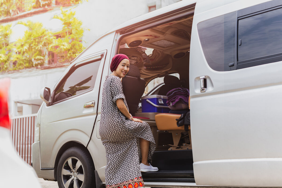 A passenger stepping up into the side door of a maxi taxi