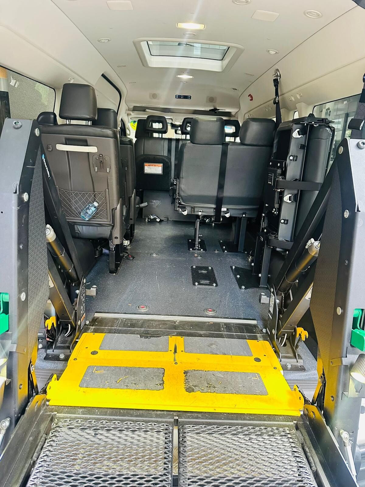 The hydraulic lift platform of a wheelchair-accessible maxi cab raised level with the floor