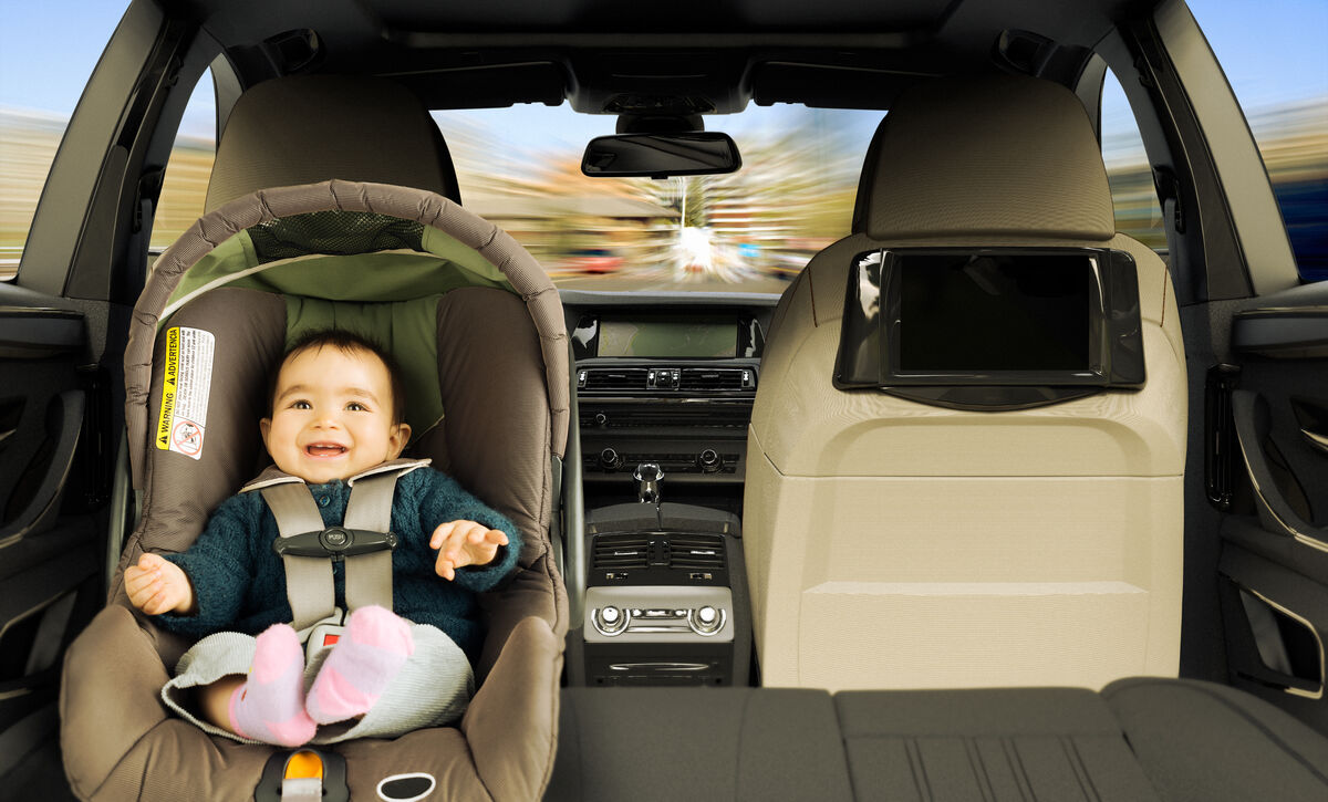 A baby seated in a rear-facing capsule in the back of a car