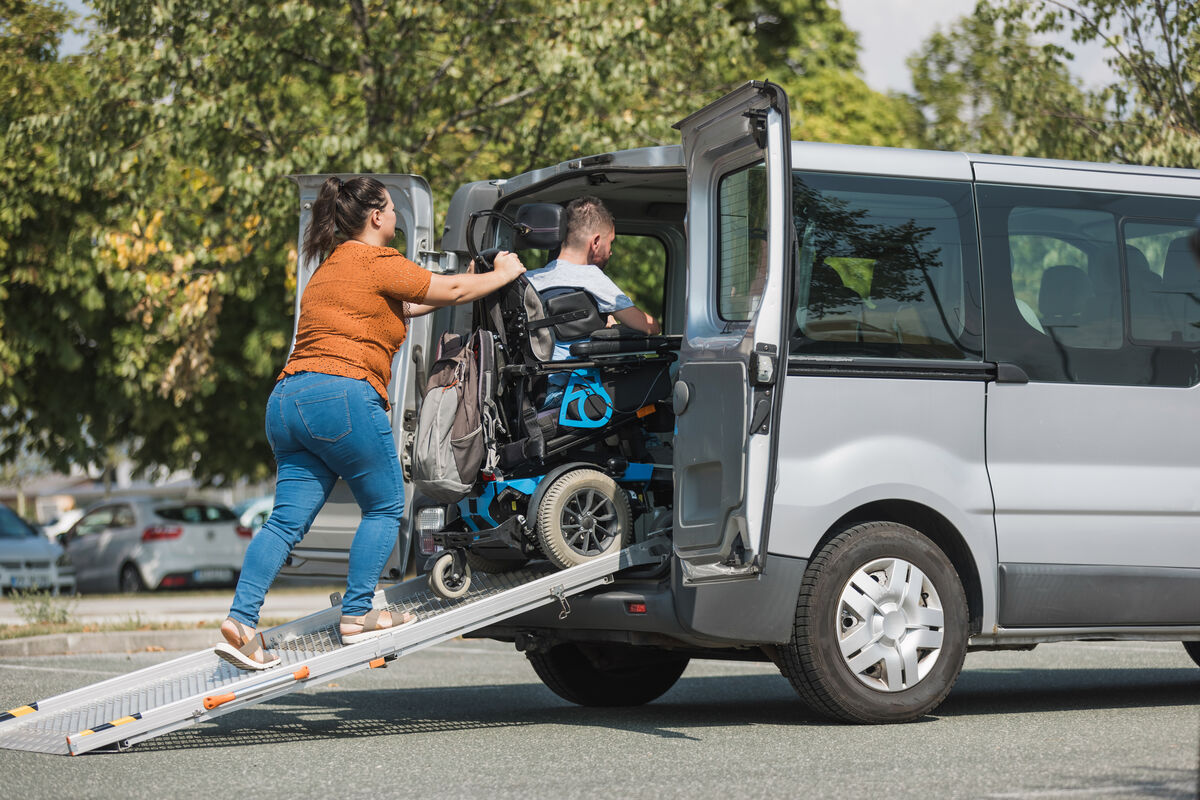 A support worker helping a participant board an accessible vehicle