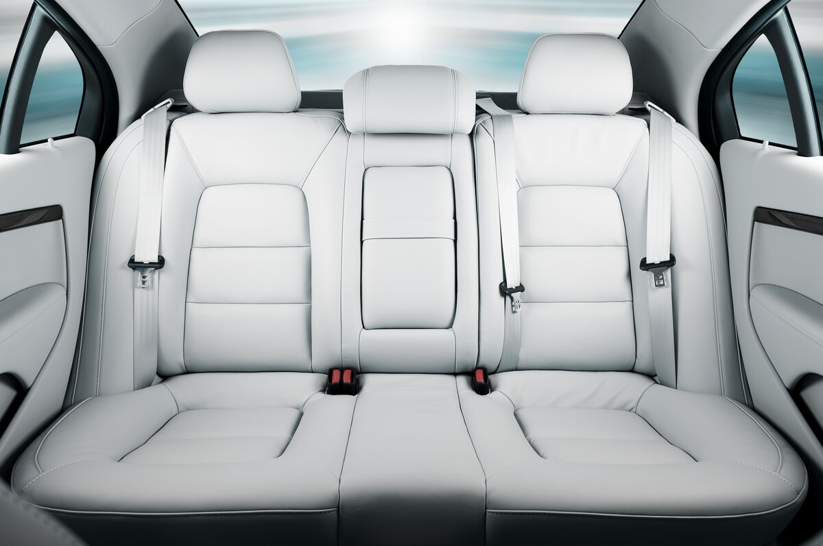 The rear passenger seats of a taxi, doors open