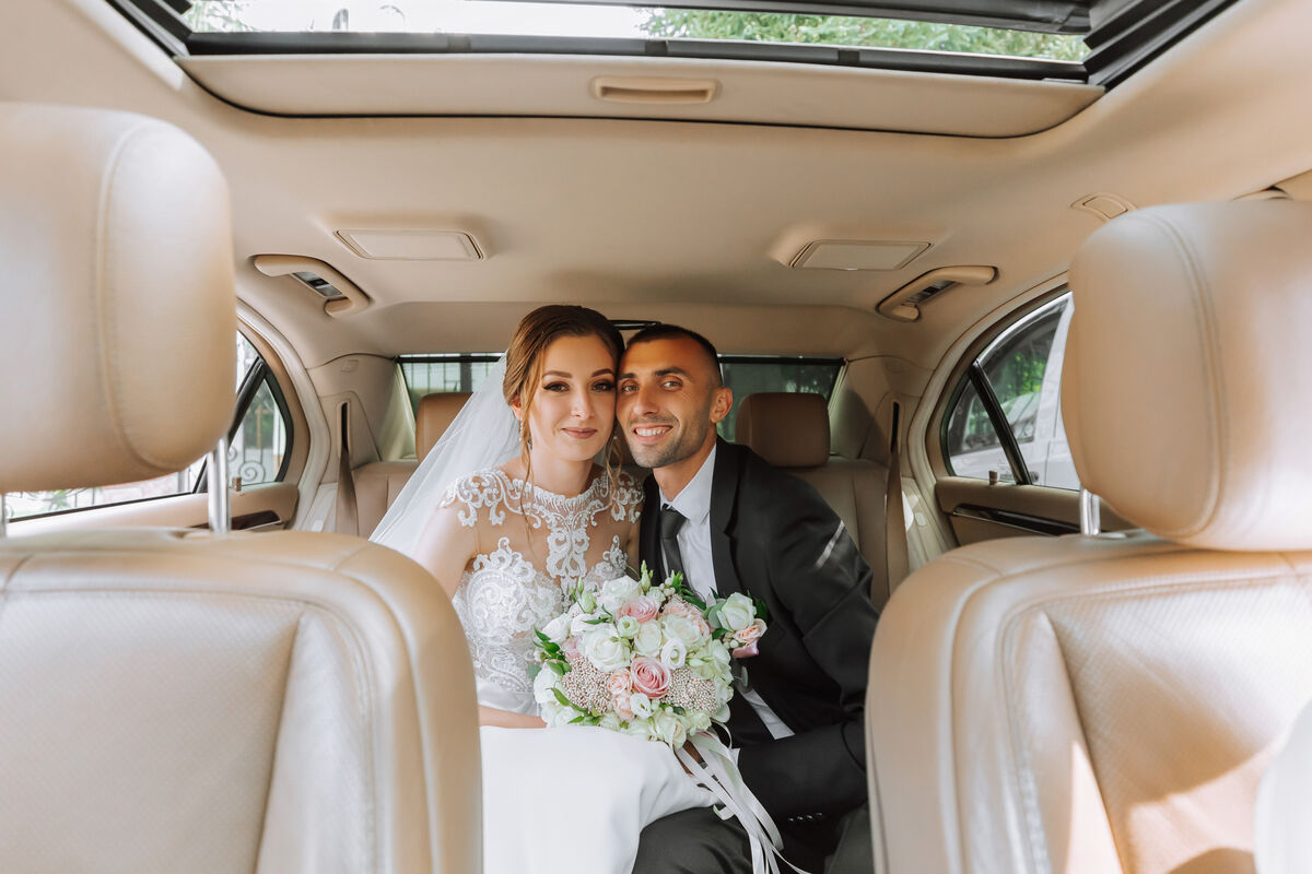 A newly married couple seated in the back of a car