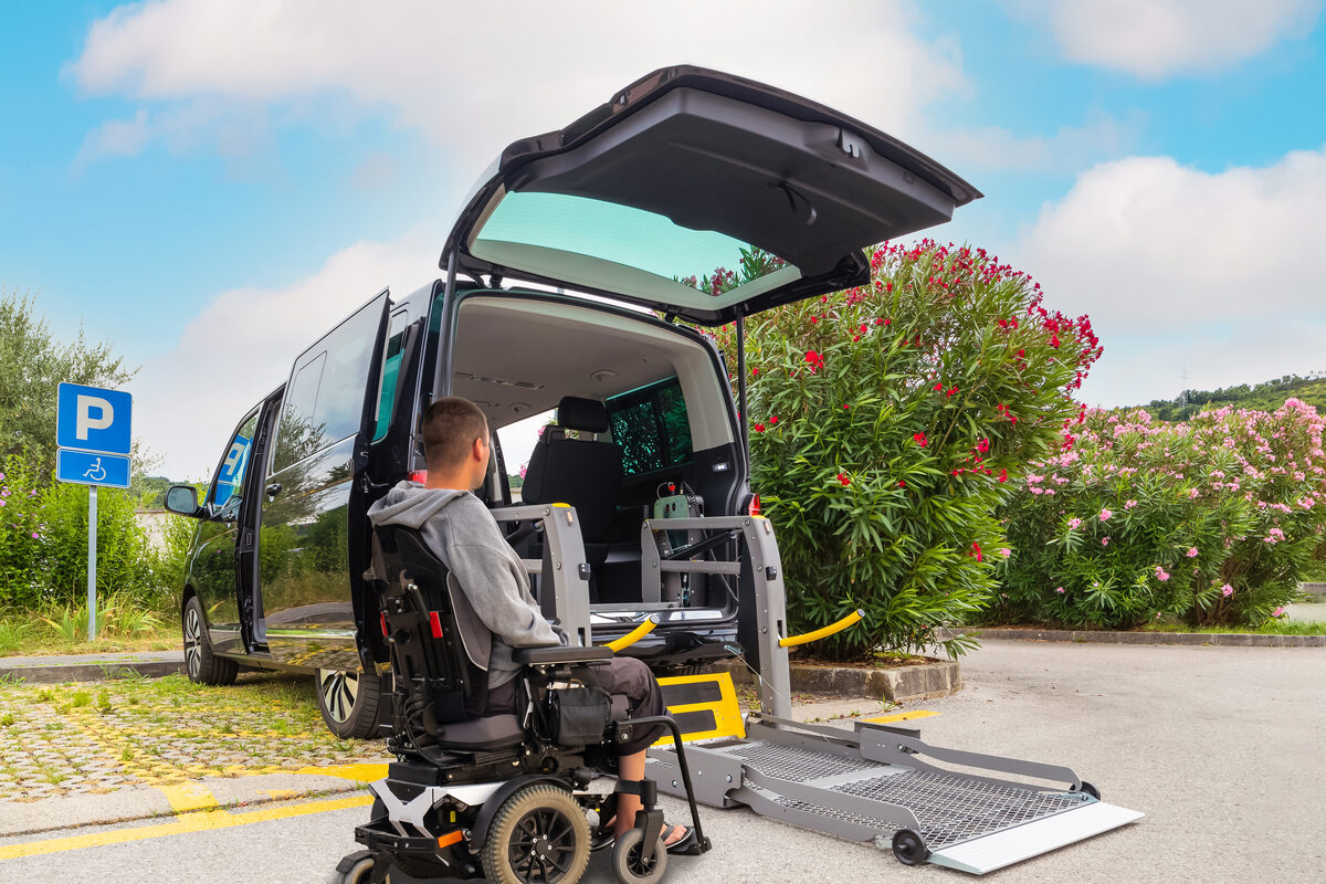 A wheelchair user boarding an accessible taxi by its rear ramp