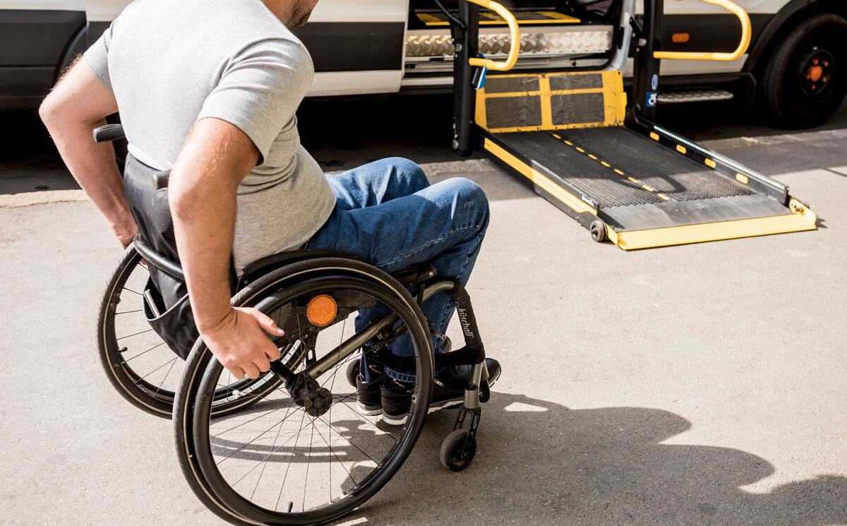 Wheelchair lift platform lowered at the side of an accessible taxi