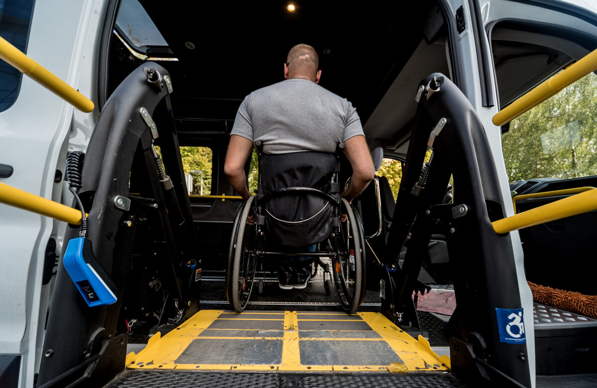A wheelchair user riding the ramp into the back of an accessible van