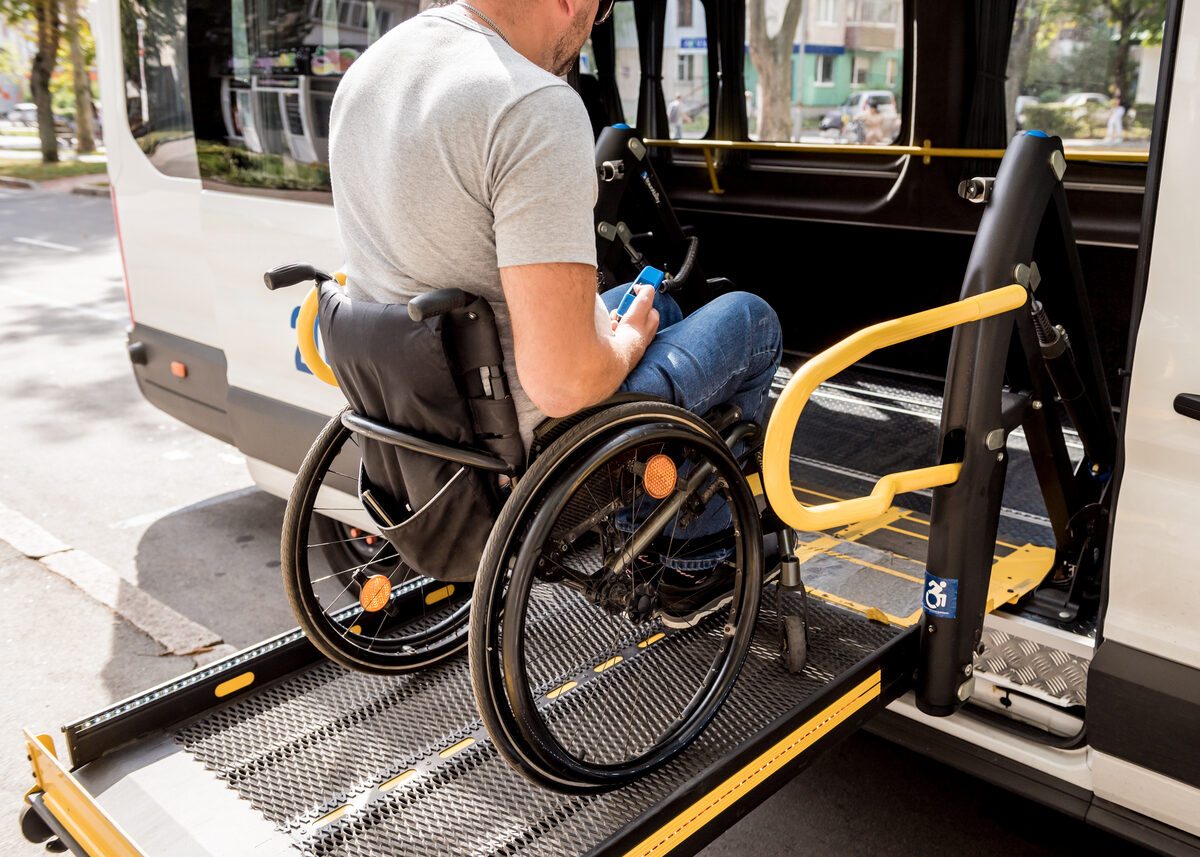 Wheelchair positioned on the lift platform between the yellow safety rails of an accessible van