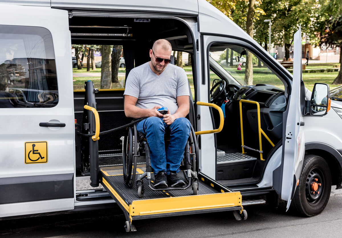 Passenger seated on the hydraulic lift platform at the side door of an accessible van
