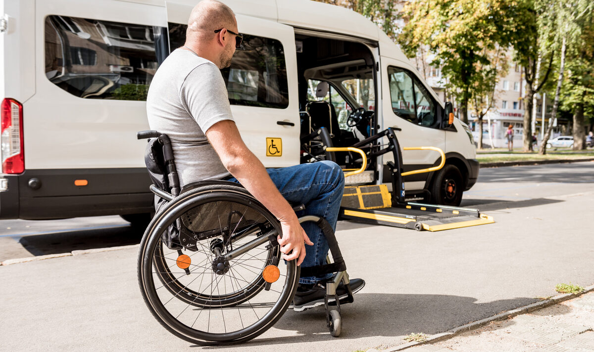 A wheelchair user boarding an accessible van from the kerb