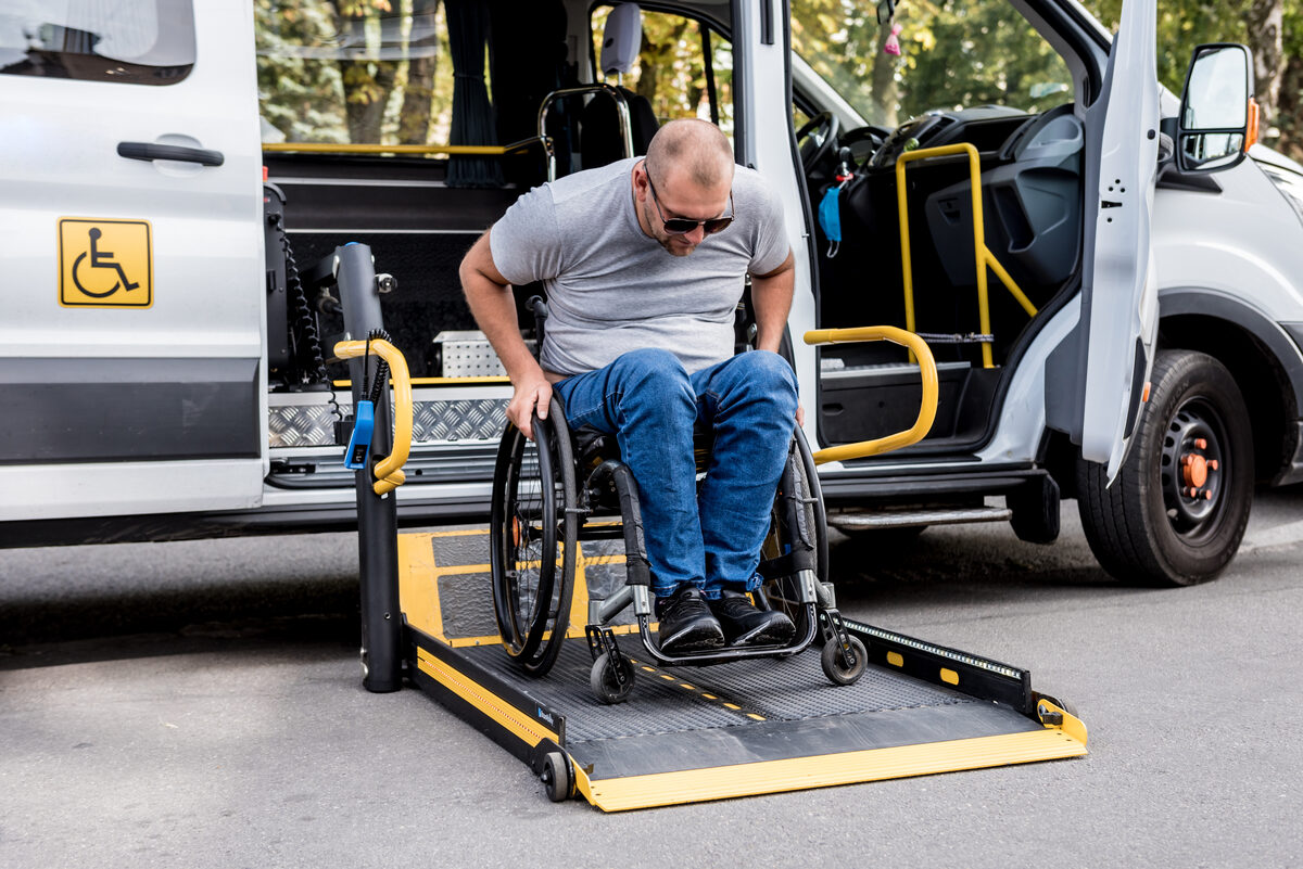 Passenger moving onto the lowered lift platform of a wheelchair-accessible van
